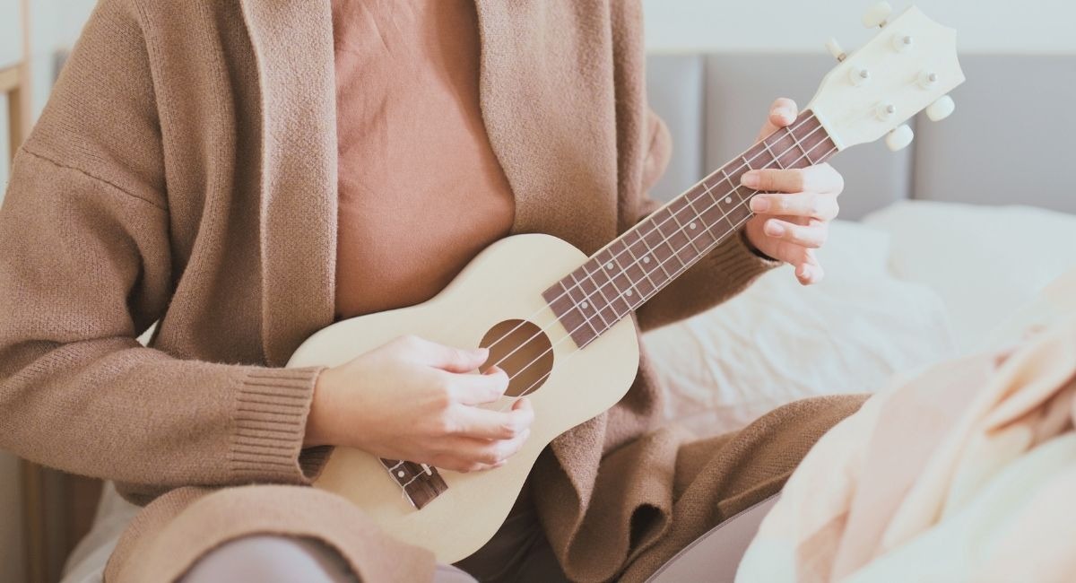 Mains jouant du ukulele en position assise dans un cadre douillet