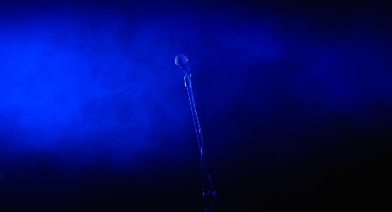 Microphone vocal sur pied éclairé par une lumière bleue sur scène