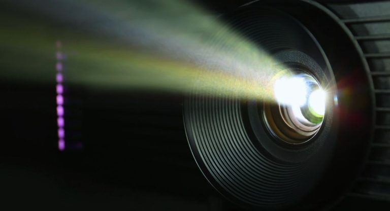 Gros plan sur l'objectif d'un videoprojecteur allume dans le noir