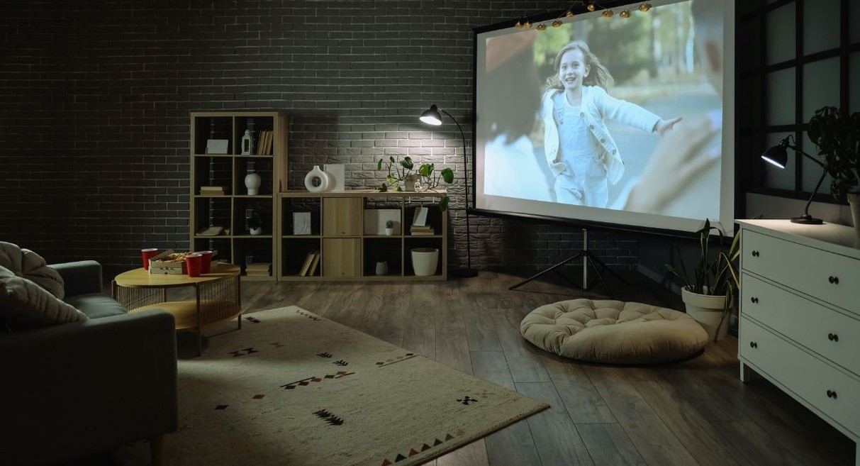Grand ecran de videoprojecteur installe sur trepied dans un salon tamise