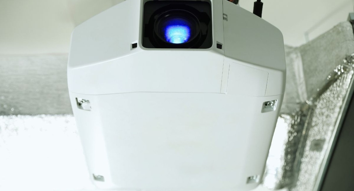 Vidéoprojecteur blanc installé au plafond, objectif visible en gros plan